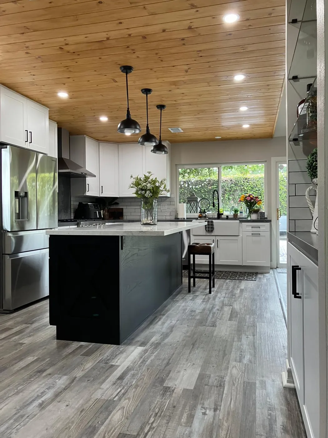Modern farmhouse kitchen with black island and wood ceiling