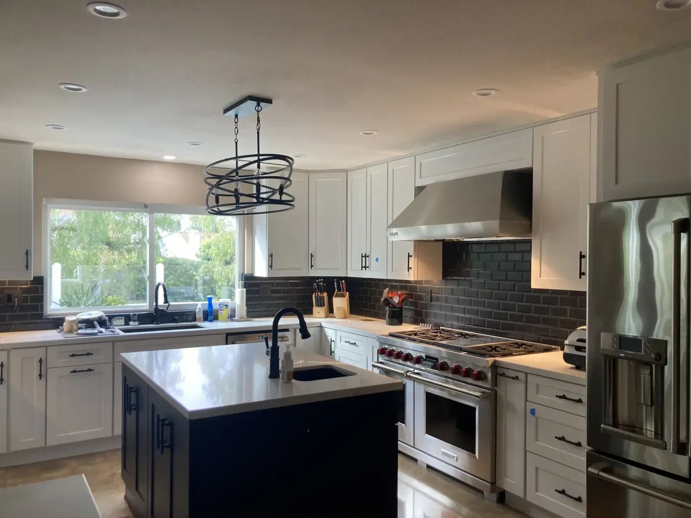 White kitchen with dark island and stainless appliances